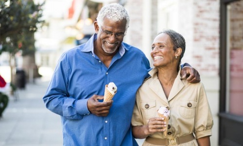 a man and woman holding ice cream cones as they walk down a city sidewalk